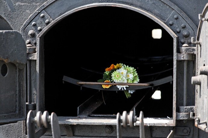 Um caixão sendo colocado em um forno cinerário para que seja realizada a cremação